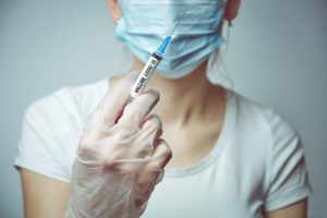 A masked nurse holds a syringe with a vaccine against the virus COVID-19.
